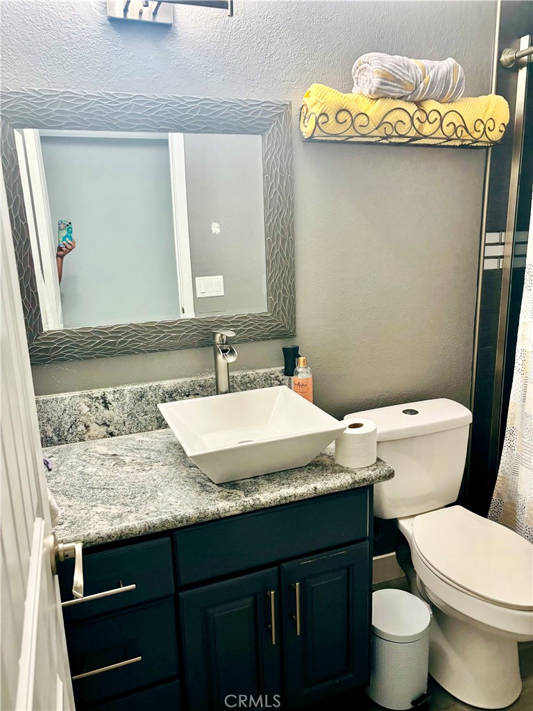 5808 Snow Line Drive Phelan, CA 92371 - Photo 14 of 15 a bathroom with a granite countertop toilet sink and mirror