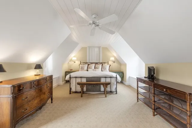 a spacious bedroom with a bed a chandelier and dresser