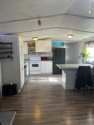 a kitchen with stainless steel appliances kitchen island granite countertop a refrigerator a stove and a wooden floors