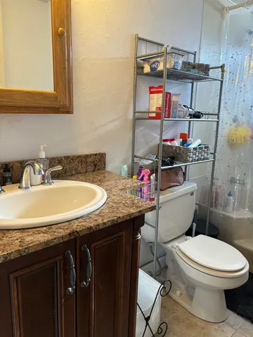 a bathroom with a granite countertop toilet sink and mirror