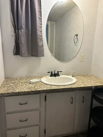 a bathroom with a granite countertop sink and a mirror