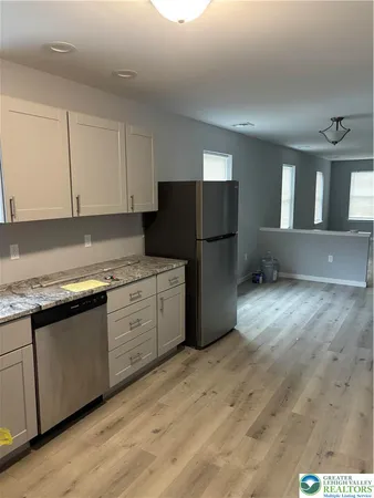 a kitchen with granite countertop white cabinets and refrigerator