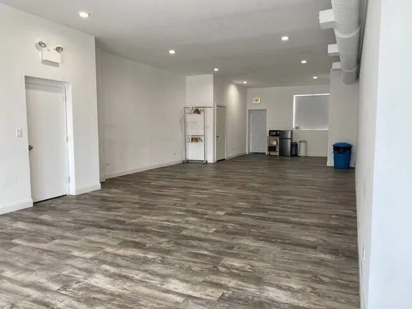 a view of an empty room with kitchen and furniture