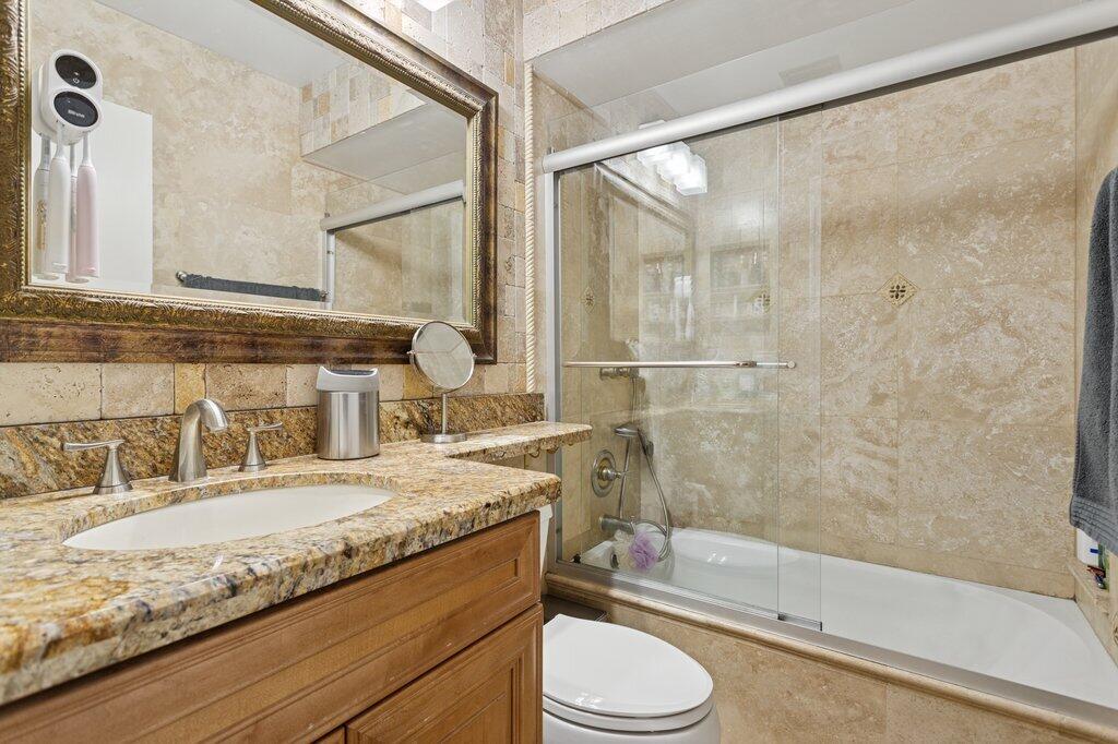 10272 Hidden Springs Court Boca Raton, FL 33498 - Photo 17 of 25 a bathroom with a granite countertop bathtub shower sink vanity mirror and toilet