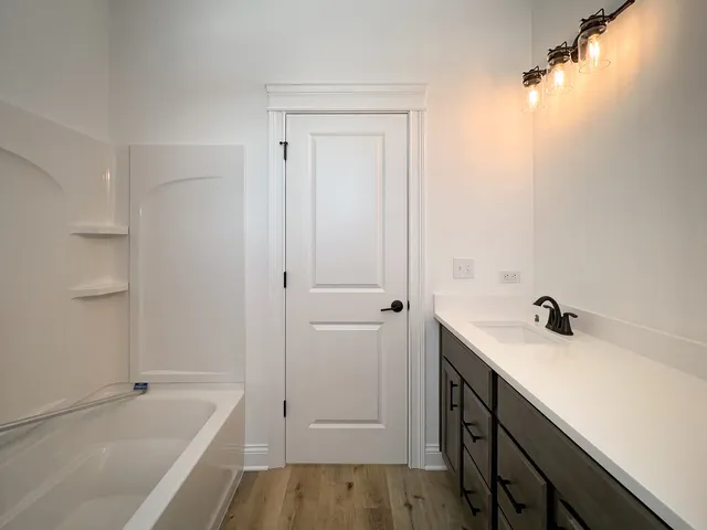 a bathroom with a tub sink vanity and a mirror