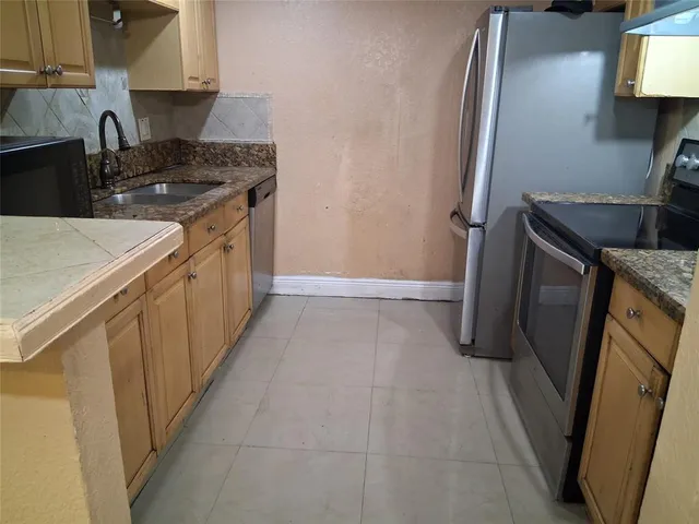 a kitchen with stainless steel appliances granite countertop a sink a stove and a refrigerator