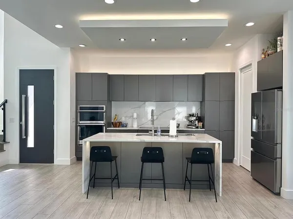 a kitchen with stainless steel appliances a table chairs refrigerator and cabinets