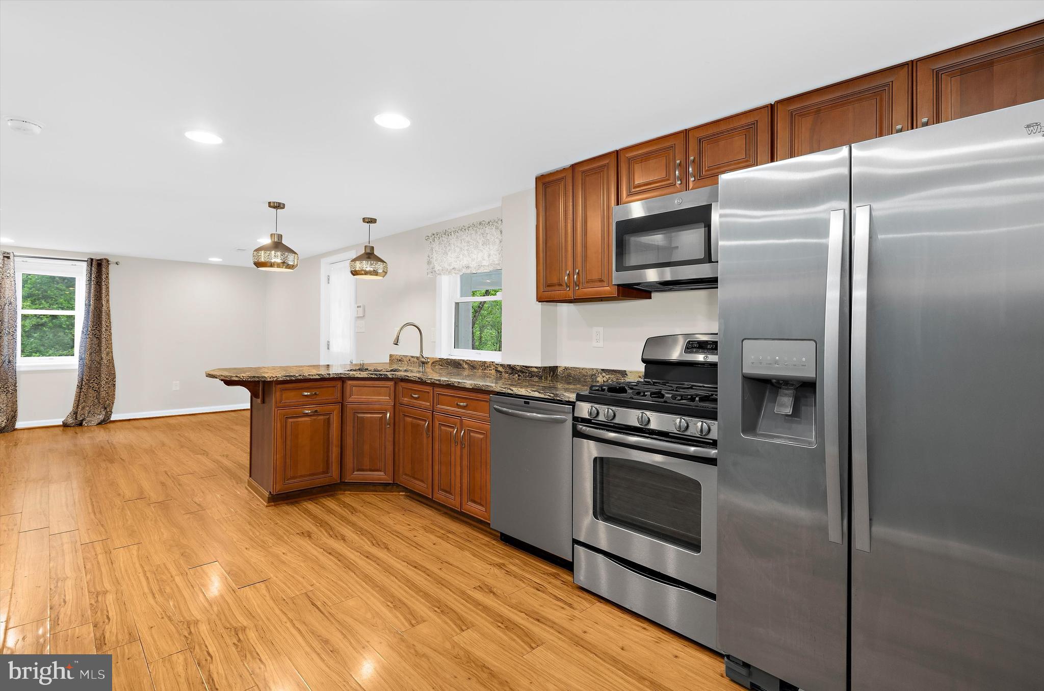 1159 Dicus Mill Road Millersville, MD 21108 - Photo 36 of 81 a kitchen with stainless steel appliances granite countertop a refrigerator a stove and a sink with wooden floor