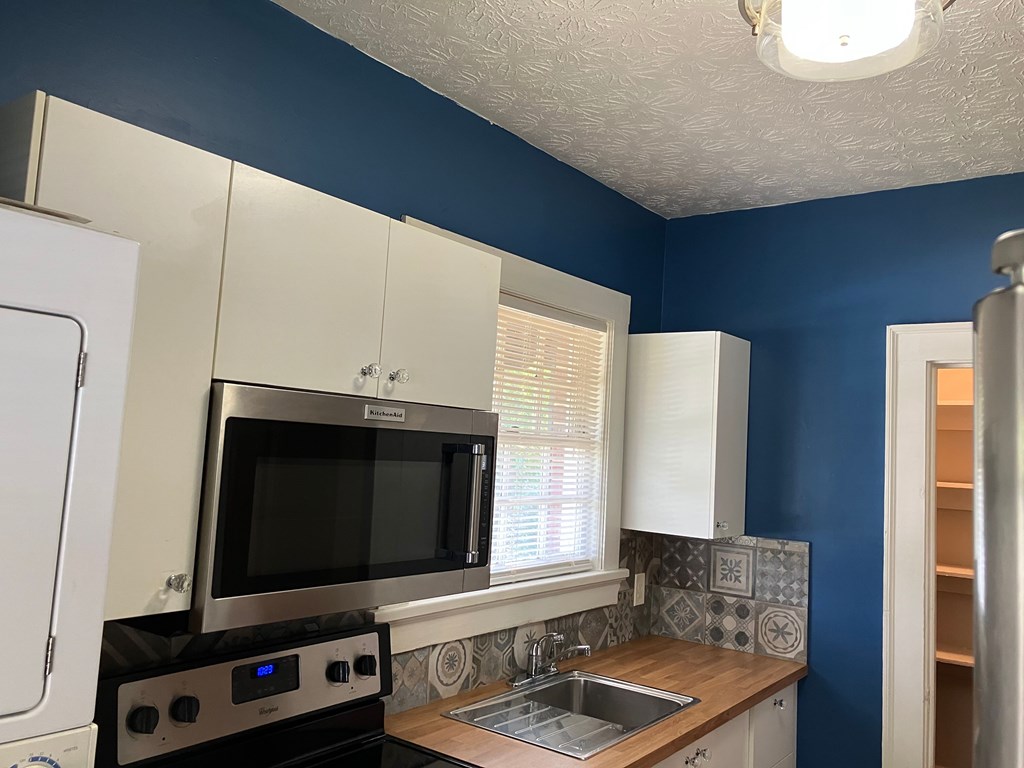 2318 Huggins Street Columbus, GA 31903 - Photo 31 of 40 a kitchen with stainless steel appliances a microwave stove and white cabinets with wooden floor
