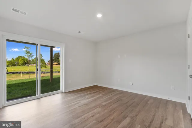 a view of empty room with wooden floor and floor to ceiling window