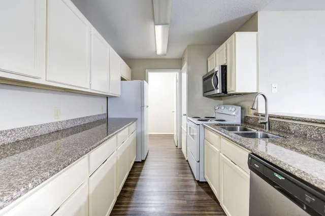 a large kitchen with stainless steel appliances granite countertop a sink and dishwasher a stove top oven with wooden floor