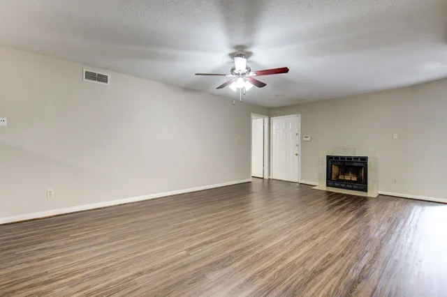 a view of an empty room with wooden floor and a fireplace