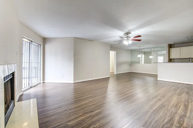 a view of an empty room with window and wooden floor