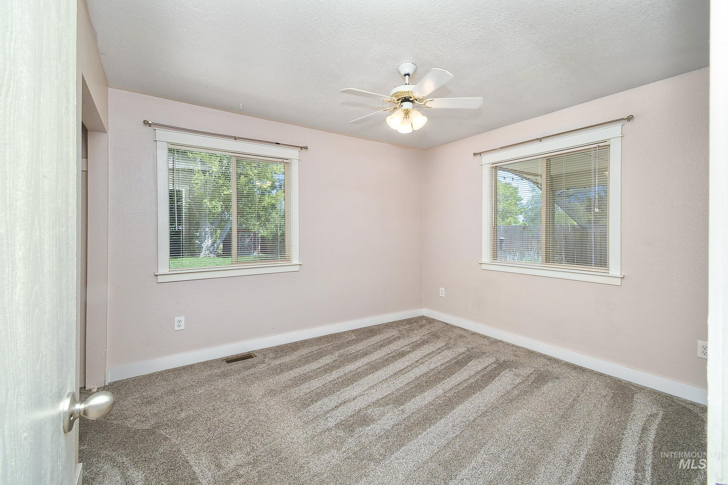 1108 East Ustick Road Caldwell, ID 83607 - Photo 18 of 30 Spacious room featuring new carpet, two windows with blinds, a ceiling fan with integrated lighting, and neutral wall tones