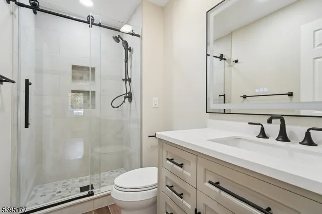 a bathroom with a shower sink vanity mirror and toilet