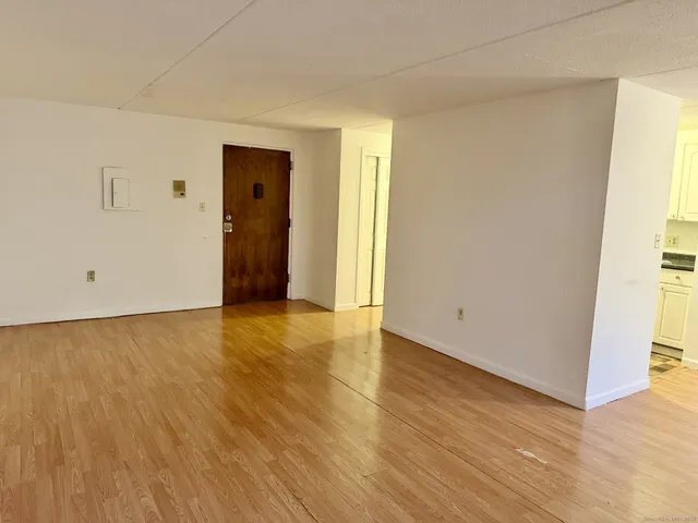 a view of an empty room with wooden floor and closet
