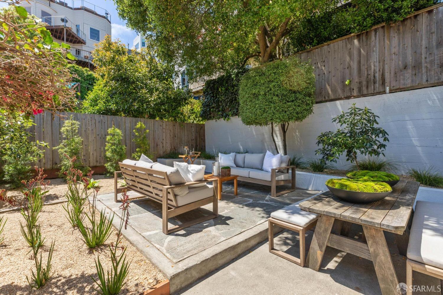 a view of a backyard with table and chairs potted plants and wooden fence