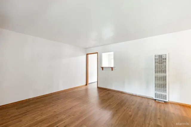 an empty room with wooden floor & windows