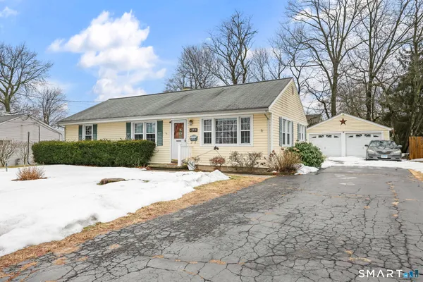 a view of a house with snow on the road and large trees