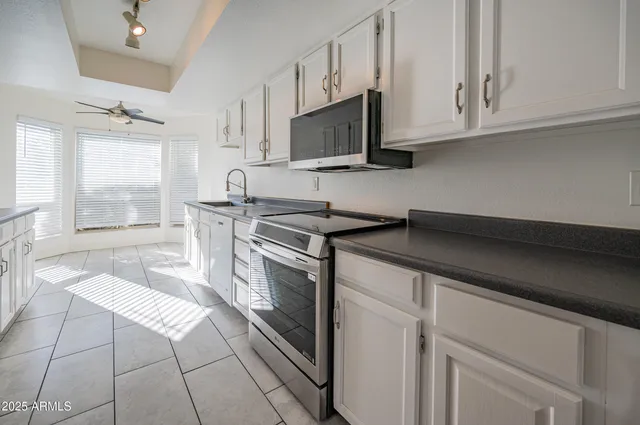 a kitchen with stainless steel appliances white cabinets and a stove top oven