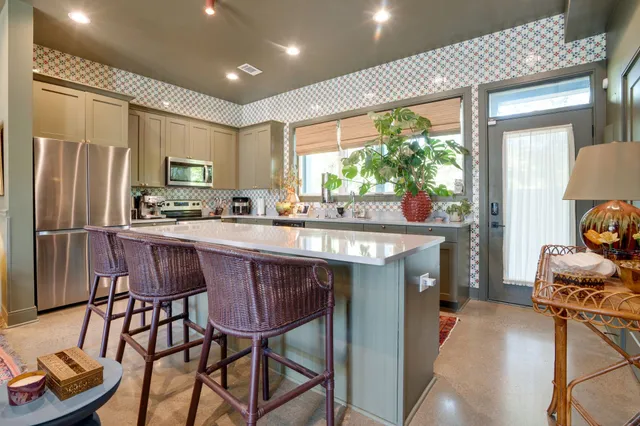 a dining room with stainless steel appliances granite countertop a table chairs and a refrigerator