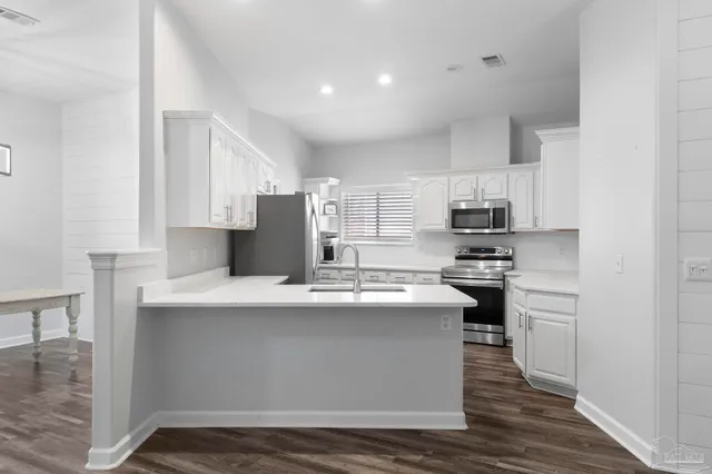 a kitchen with stainless steel appliances a sink stove and white cabinets