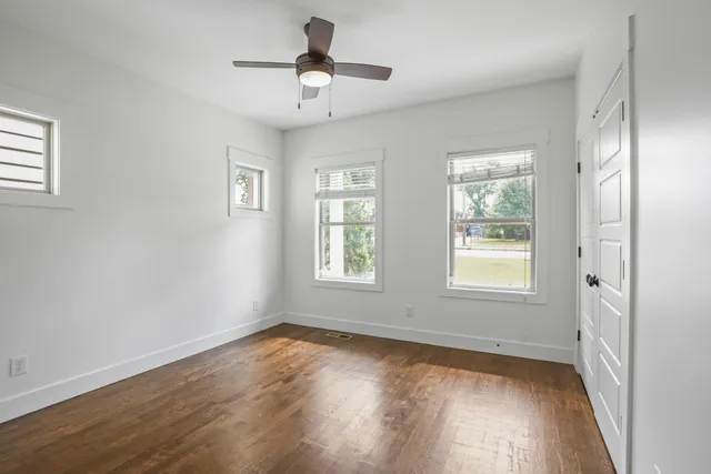 a view of an empty room with wooden floor and a window
