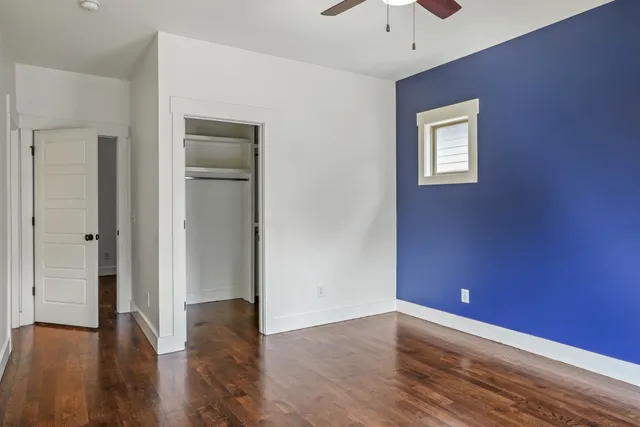 a view of an empty room with a window and wooden floor