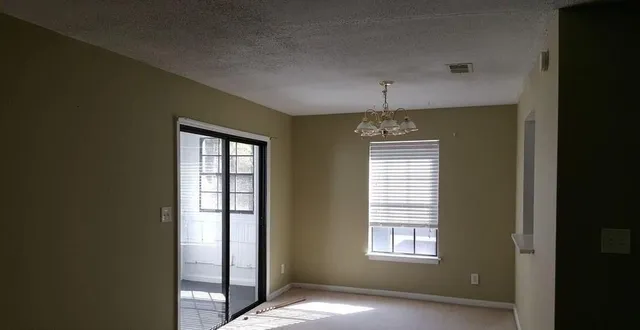 an empty room with windows and ceiling fan