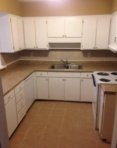 a kitchen with granite countertop white cabinets and white appliances