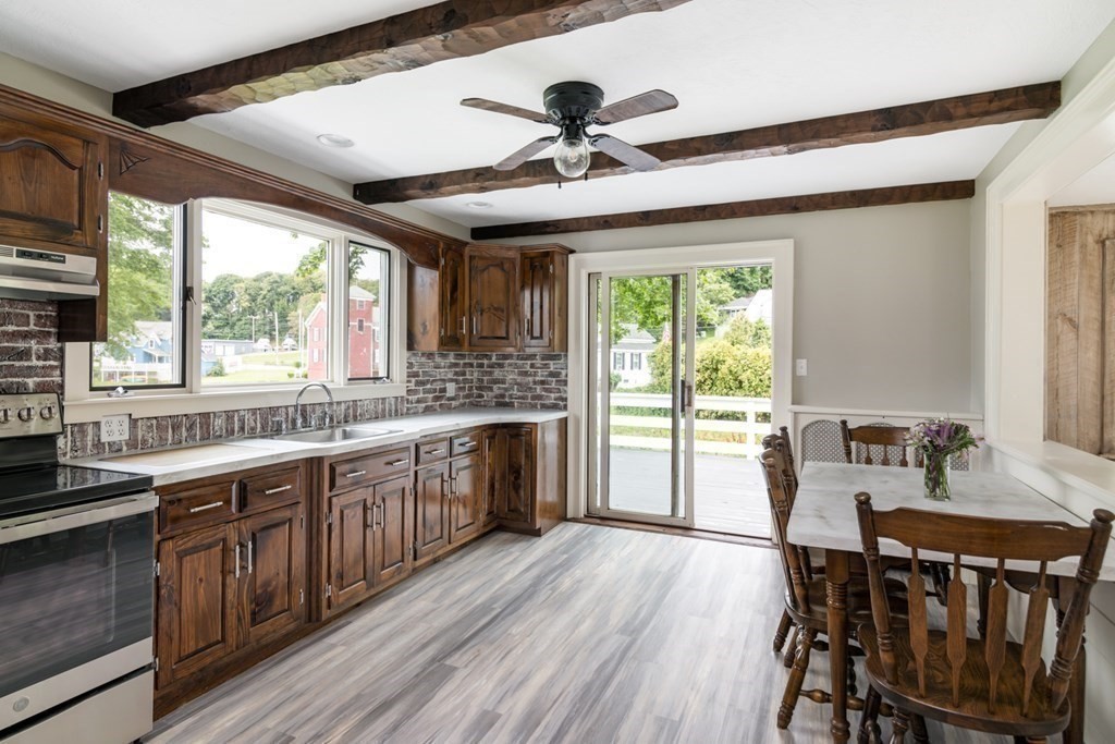 24 Main Street Hull, MA 02045 - Photo 10 of 19 a kitchen with stainless steel appliances granite countertop a stove a refrigerator a sink dishwasher a dining table and chairs with wooden floor