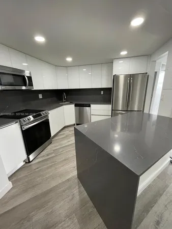 a large kitchen with stainless steel appliances a large counter top a stove and a refrigerator
