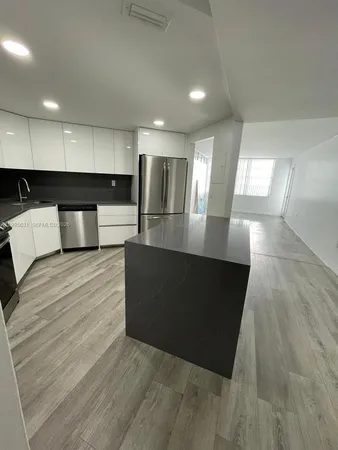 a large room with kitchen island granite countertop a couch and a counter top space