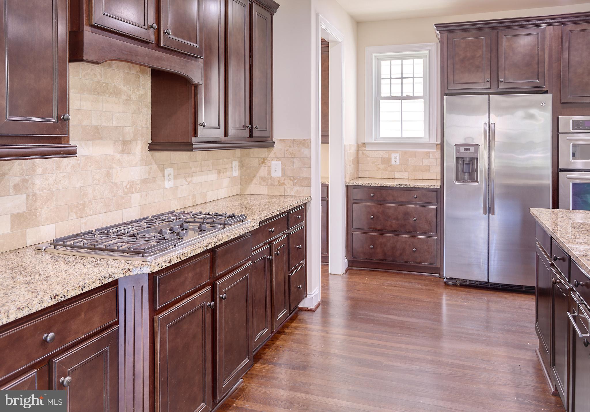 13501 Moonlight Trail Drive Silver Spring, MD 20906 - Photo 21 of 77 a kitchen with granite countertop a refrigerator and wooden cabinets