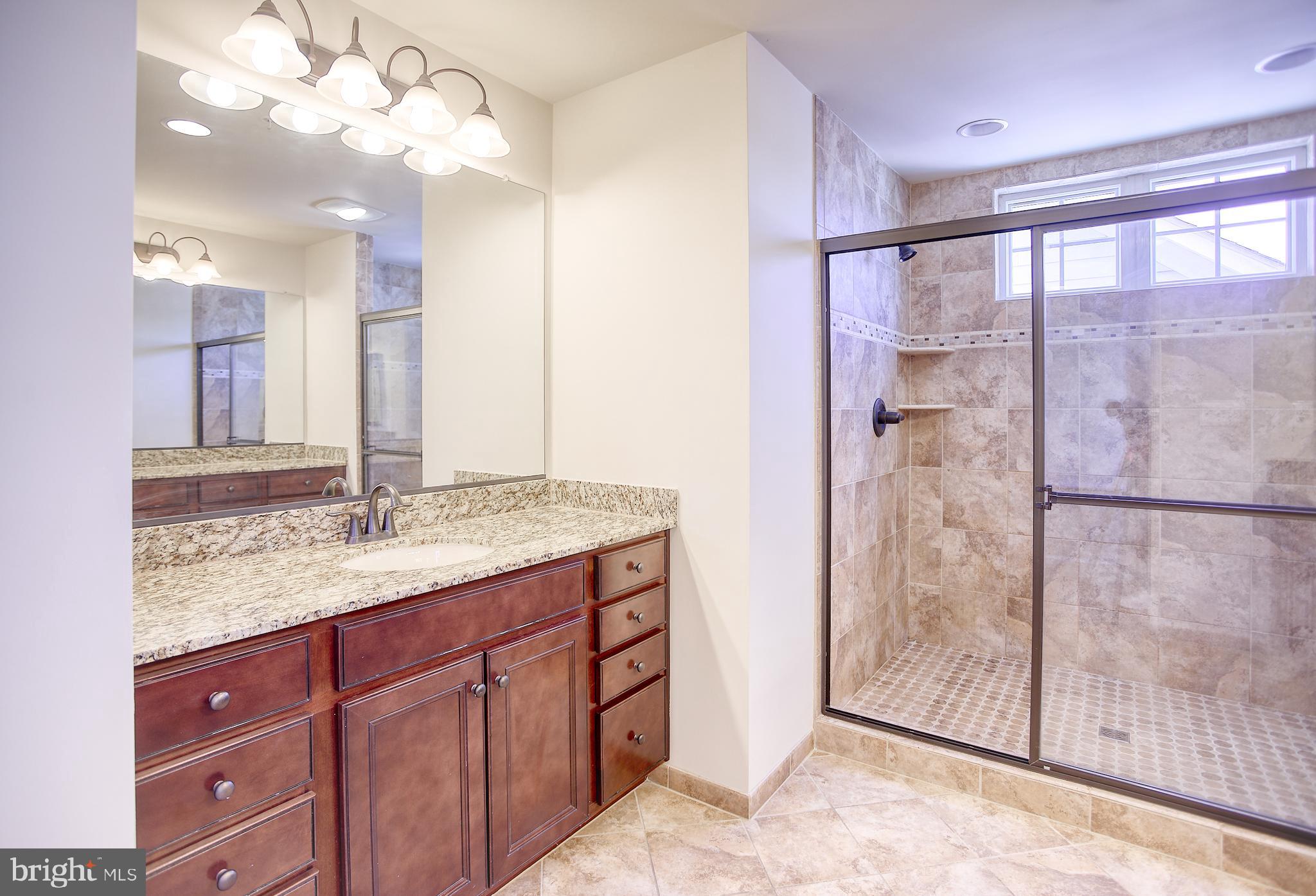 13501 Moonlight Trail Drive Silver Spring, MD 20906 - Photo 40 of 77 a bathroom with a granite countertop sink a mirror and a shower
