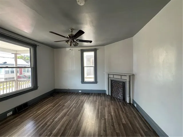 an empty room with wooden floor a ceiling fan and windows