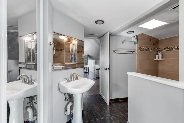 a bathroom with a sink shower and a mirror