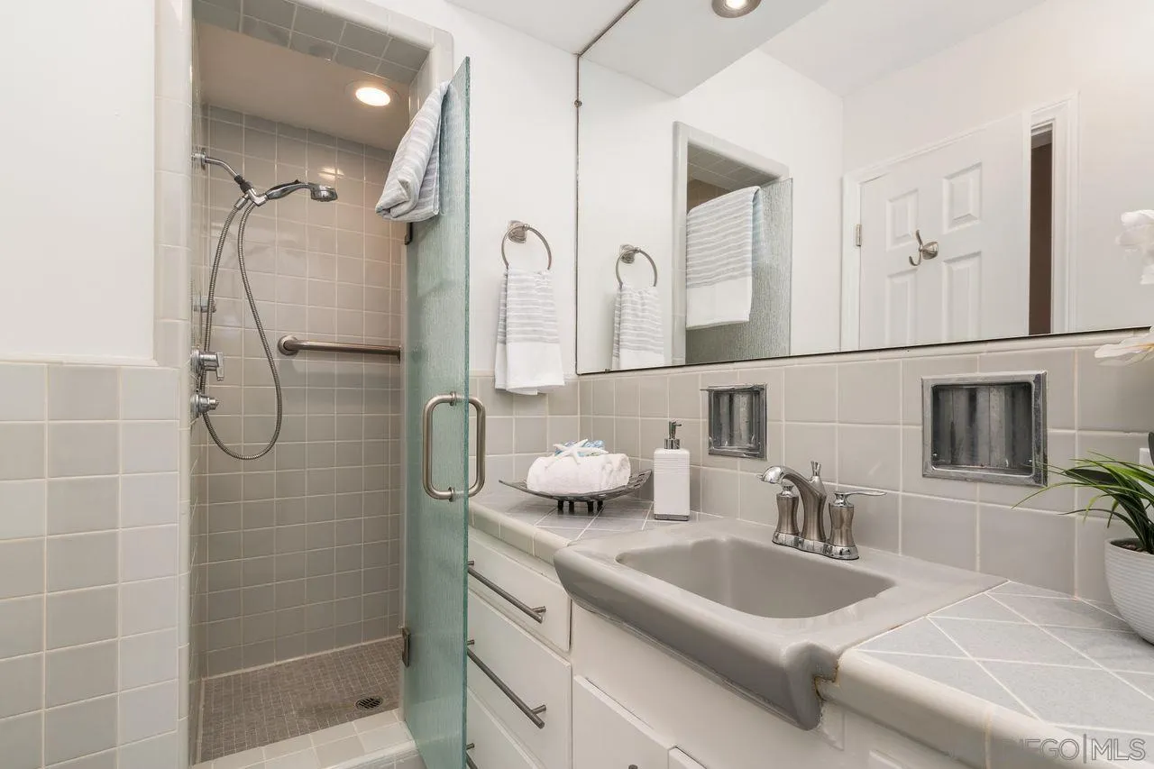 2362 Torrey Pines Road, Unit 33 La Jolla, CA 92037 - Photo 19 of 32 a bathroom with a granite countertop sink a mirror a vanity and shower