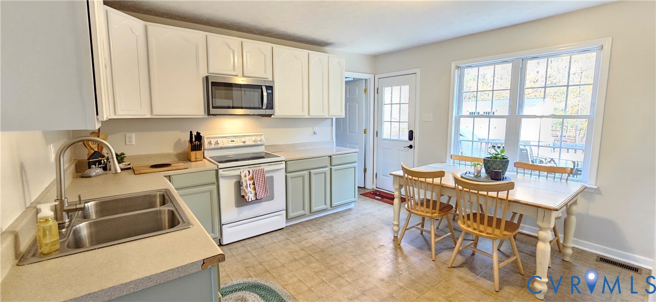 2239 Mantapike Landing Road Stevensville, VA 23161 - Photo 17 of 22 a kitchen with stainless steel appliances granite countertop a stove top oven a sink a dining table and chairs with wooden floor
