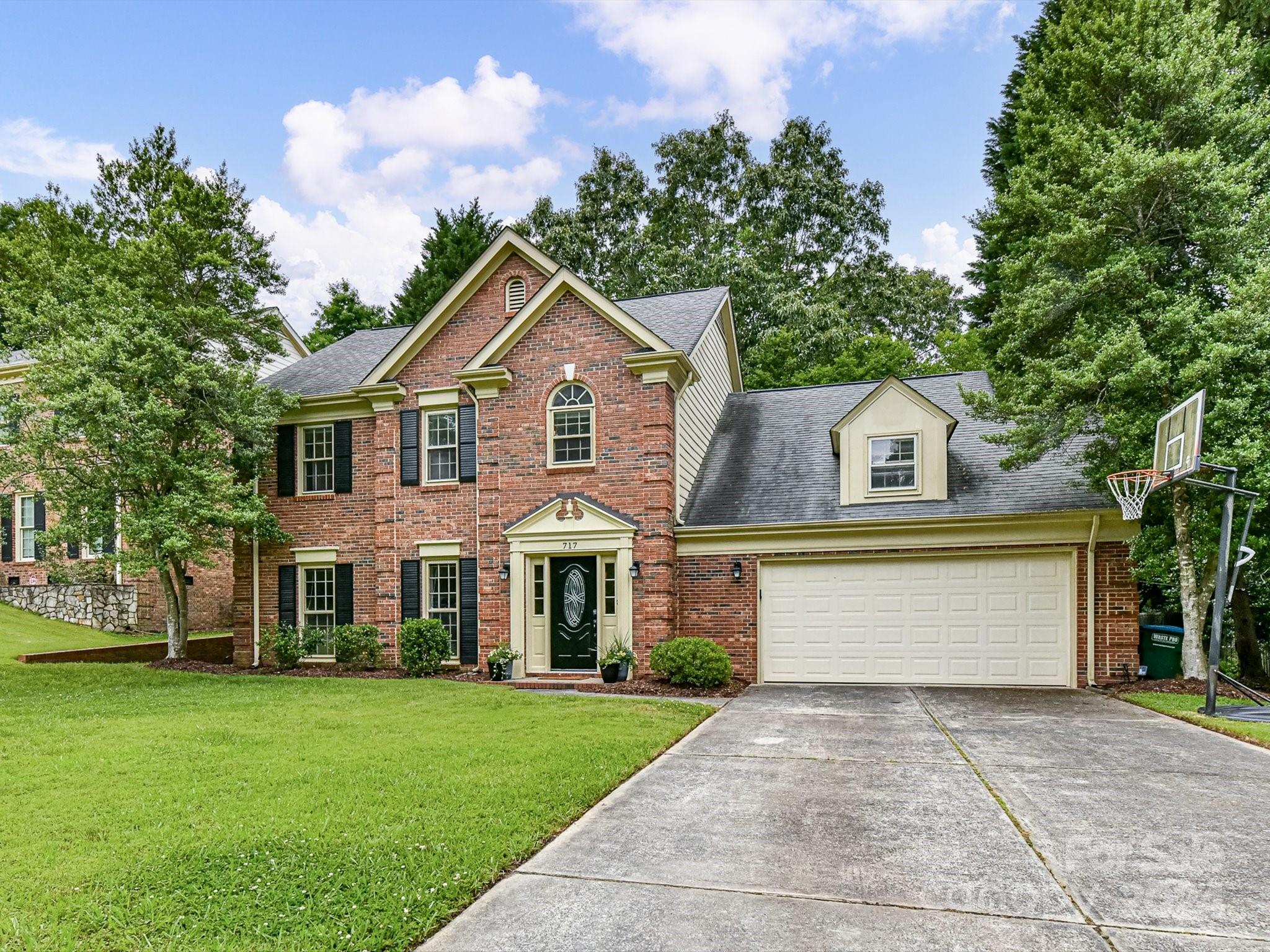 a front view of a house with a garden and trees