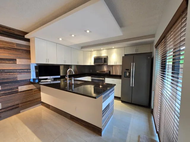 a kitchen with stainless steel appliances granite countertop a sink and a refrigerator