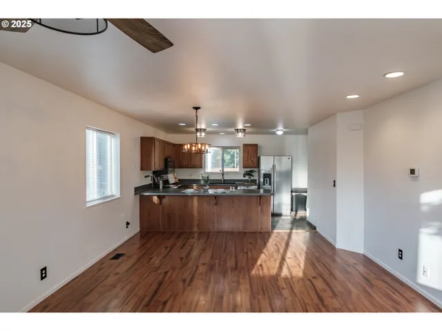 a open kitchen with kitchen island a sink dishwasher a refrigerator and wooden floor