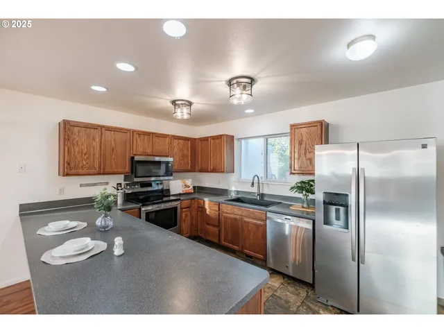 a kitchen with stainless steel appliances granite countertop a refrigerator a sink dishwasher a stove with wooden cabinets