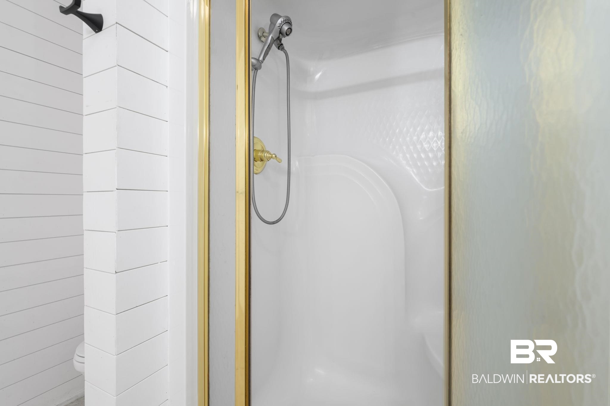 7540 2 Mile Road Irvington, AL 36544 - Photo 36 of 82 White shower stall with a gold-finish frame, textured glass, and a handheld showerhead