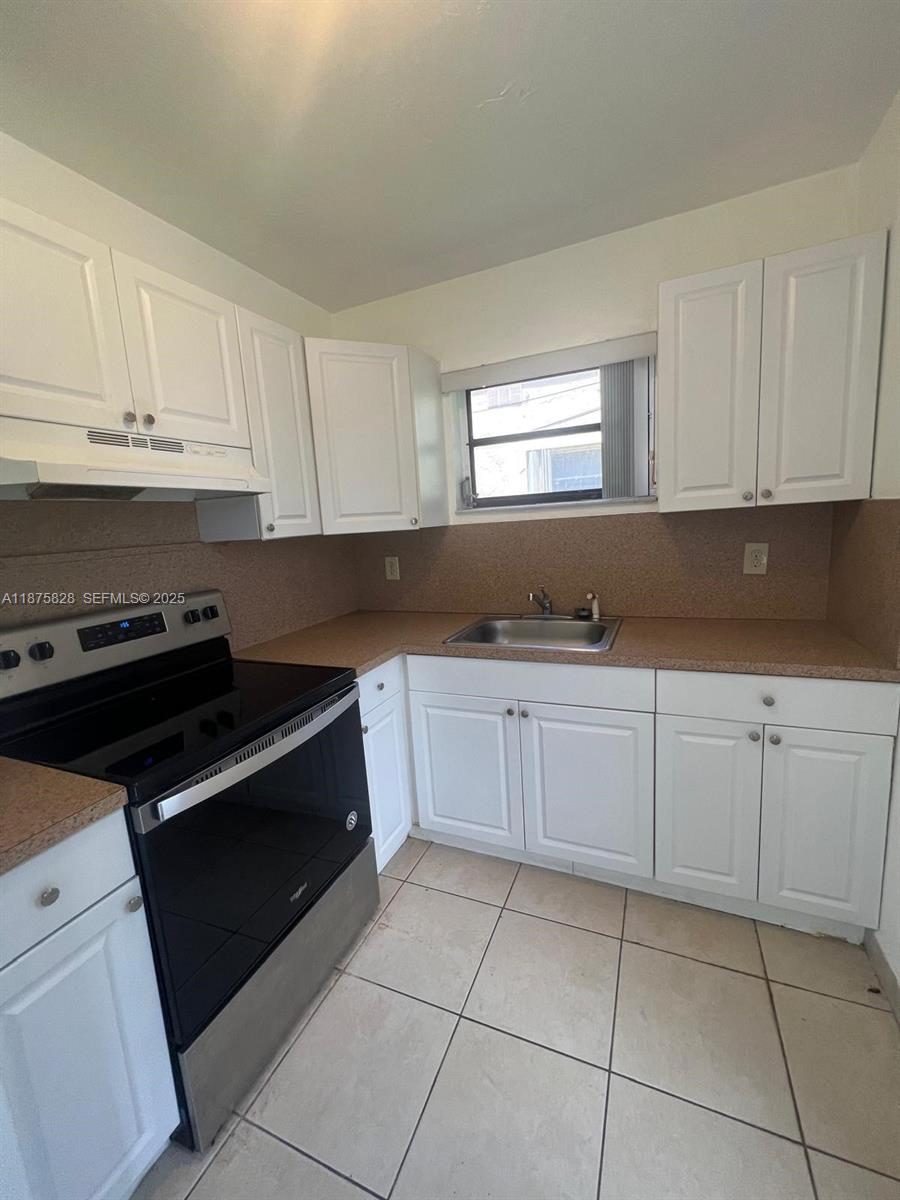 1670 Harding Street Hollywood, FL 33020 - Photo 17 of 19 a kitchen with granite countertop white cabinets and black appliances