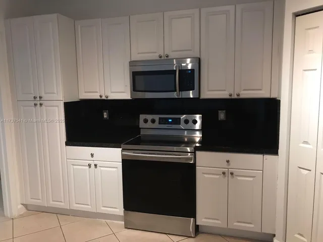 a kitchen with granite countertop white cabinets and black appliances
