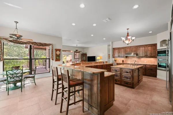 a kitchen with stainless steel appliances granite countertop table chairs stove and sink