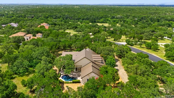 an aerial view of residential houses with outdoor space and trees all around