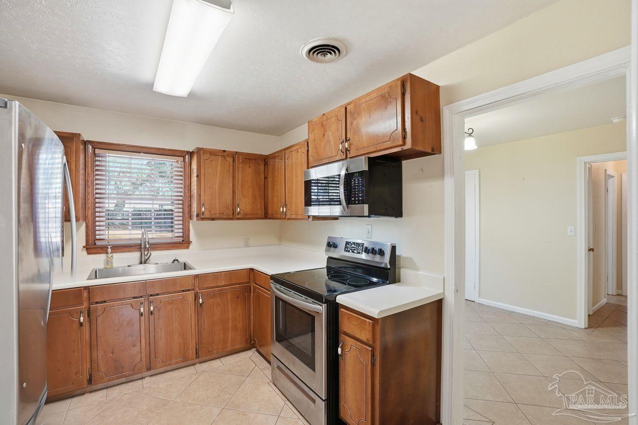 6444 Walnut Street Milton, FL 32570 - Photo 11 of 33 a kitchen with stainless steel appliances granite countertop a sink stove and microwave