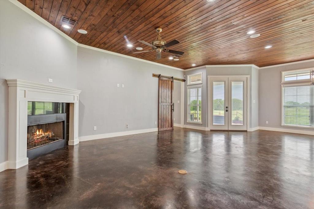 259 County Road 149 Riesel, TX 76682 - Photo 7 of 40 Unfurnished living room with wood ceiling, a barn door, concrete floors, ornamental molding, and ceiling fan